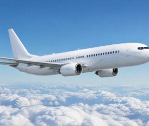 Weißes Passagierflugzeug fliegt bei blauem Himmel über einer geschlossenen Wolkendecke