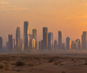 Skyline mit gläsernen Hochhäusern am Rand der Wüste in der Abenddämmerung