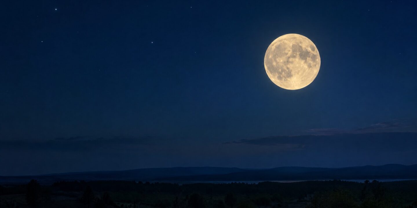 Heller Vollmond am dunkelblauen Nachthimmel über einer stillen Landschaft