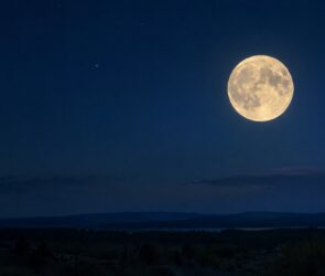 Heller Vollmond am dunkelblauen Nachthimmel über einer stillen Landschaft
