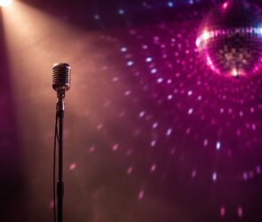 Altes Bühnenmikrofon im Lichtkegel vor einer glitzernden Discokugel